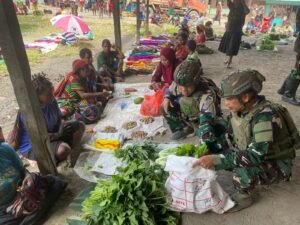Personil Pos Sinak Satgas Yonif 700/WYC Belanja Hasil Tani Masyarakat di Pasar Sinak mama Papua tersenyum Bahagia
